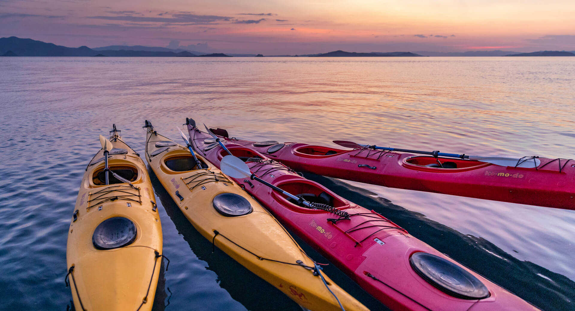 Nomad Kayaks 1 Nomad Kayaks -Nomad Kayaks komodo indonesia colorful kayaks bound together on the ocean at sunset adobe stock 2865